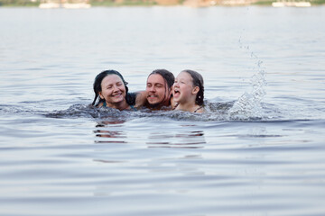 Smiling family members laughing and bonding as they swim in the peaceful lake waters. Joyful...