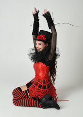 Burlesque circus performer, fantasy female model in halloween jester clown costume with top hat,...