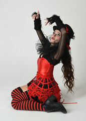 Burlesque circus performer, fantasy female model in halloween jester clown costume with top hat,...