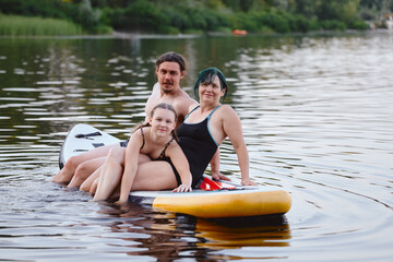 Family Enjoying Paddleboarding on a Peaceful Lake During a Sunny Day