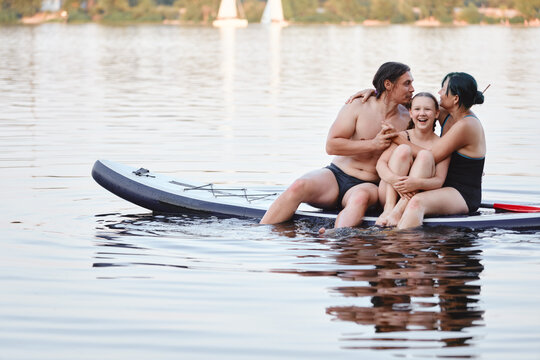Family of Three Enjoys Paddleboarding Together on a Calm Lake