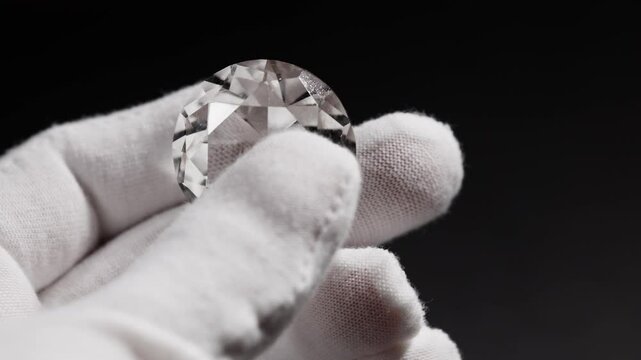 Closeup of hands of diamond expert in process of evaluating polished diamonds using jewellery tools.