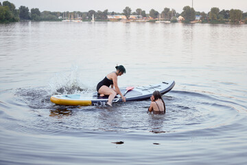 Two Friends Enjoying Fun Paddleboarding Experience in Serene Outdoor Waters at Sunset