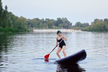 Woman Paddleboarding on a Calm Lake Near a Natural Beach