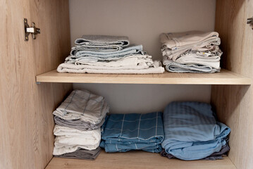 Bed linen, sheets and pillowcases and towels neatly stacked in closet in bedroom