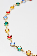 Elegant Gold Chain With Multicolored Gemstones on a Light Background