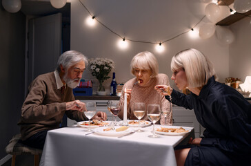 Three family members savor a beautifully prepared meal during a festive dinner in a warmly...