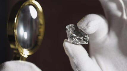 Man jeweller examines polished diamond through magnifier. Buyer checking diamond. Cut and polished diamond. Diamond jewellery under grading. Jeweller looking through loupe.