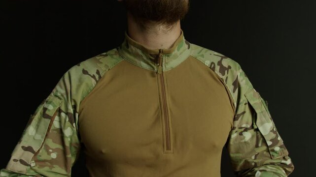 Soldier zips up the neck of tactical multicam camouflage clothing