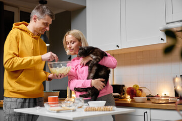 Couple Enjoying Cooking Together in Cozy Kitchen with Their Pet Cat