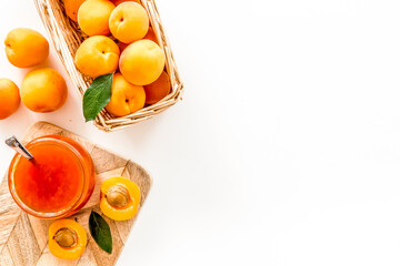 Summer preserves. Apricot jam in jar near fresh fruits on white background top view frame copy space