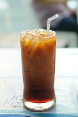 A Glass of Ice Thai Milk Tea or Cha Yen with blurred background.