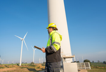 Engineer wearing uniform inspection and survey work in wind turbine farms rotation to generate...