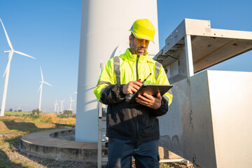 Engineer wearing uniform inspection and survey work in wind turbine farms rotation to generate electricity energy. Maintenance engineer working in wind turbine farm at sunset.