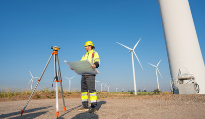 Engineer wearing uniform inspection and survey work in wind turbine farms rotation to generate electricity energy. Maintenance engineer working in wind turbine farm at sunset.