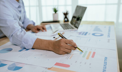 Asian businessman working at desk analyzing financial reports, charts and data using laptop to plan...