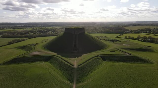 A motte and bailey castle rises majestically from a green hill, showcasing medieval architecture and historical significance in the landscape