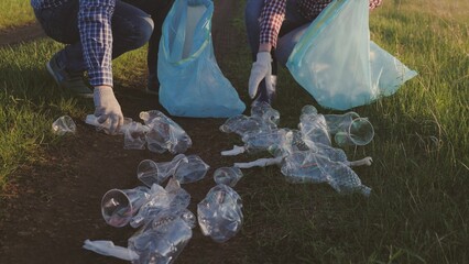 A group of people volunteers collect garbage in trash bags, cleaning the ecology of green nature from garbage, the concept of a happy family, a clean planet for a person, the environment is in danger
