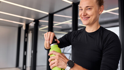 Woman Enjoys a Refreshing Drink at a Modern Indoor Gym Setting