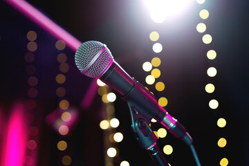 Microphone on stage against the background of spotlights. Public speaking, audio recording, karaoke...