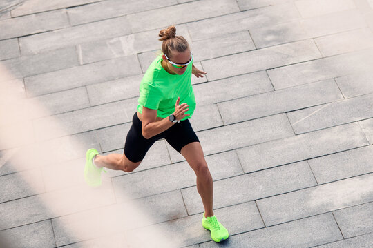 Athletic woman running on a paved walkway during a sunny day outdoors