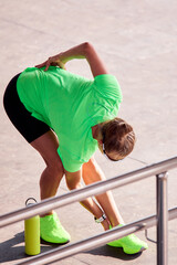 Athletic woman stretching outdoors during a workout session in bright sportswear
