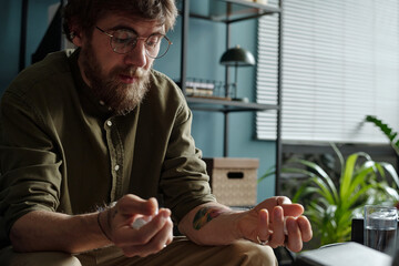 Man sitting in therapy session holding hands open while talking with therapist, showing thoughtful...