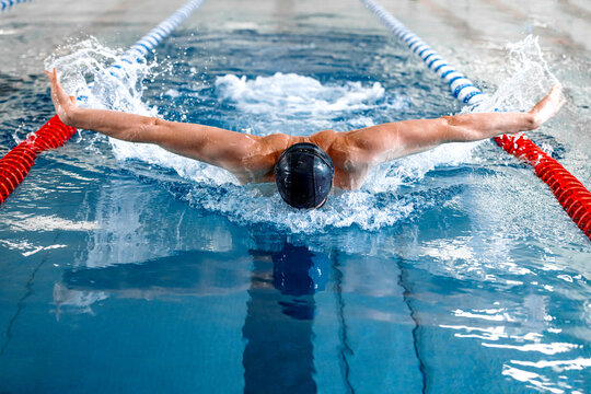 Male swimmer performing butterfly stroke in a competition swimming pool during a race