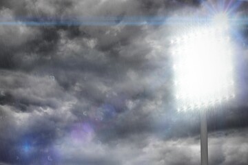 Flat design stadium floodlight tower shining through rain under overcast sky creating lens flares