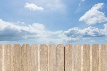 Flat design vertical wooden slat fence is stretching under bright blue sky dotted with clouds