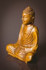 Seated wooden Buddha statue is reflecting on glossy surface in 3D render with deep brown gradient
