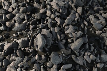 3D render is showing irregular dark grey stones overlapping on coarse gravel terrain with shadows