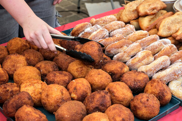 Assorted fried pastries and sugar-coated donuts stacked at a market stall, showcasing golden...