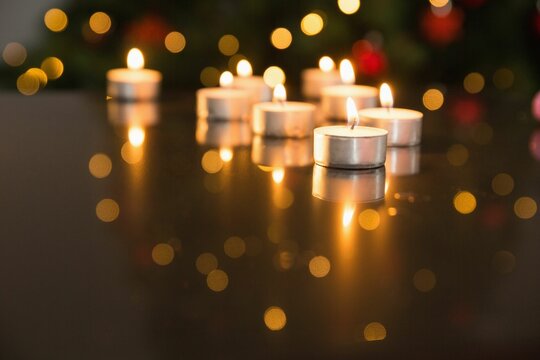 Fototapeta Lit tea light candles on glass table during christmas