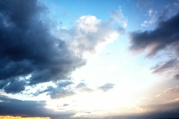 Large cloud formation is dominating flat vector sky illustration, with glowing horizon light