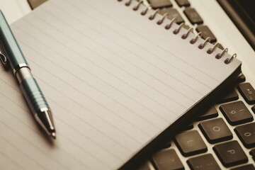 Spiral-bound notebook and ballpoint pen are resting on laptop keyboard in 3D render