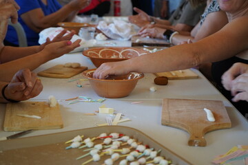 Women craft traditional Cretan sugary mantinades—tiny handmade sweets wrapped around paper cones containing poetic or satirical verses. A unique blend of dessert and folk storytelling.