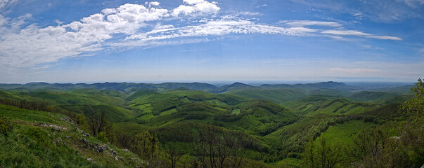 Sweeping wide-angle panorama of the vast green forest landscape and distant hills seen from the Három-kő plateau. © Tibor