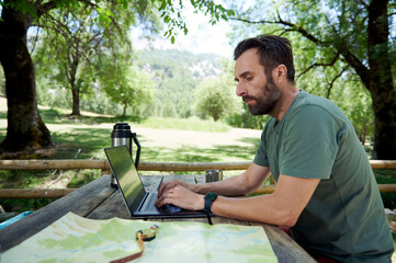 Remote Work Outdoors: A Man Uses a Laptop While Traveling in Nature