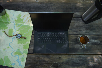 Outdoor Workstation Setup with a Laptop, Map, Compass, and Tea