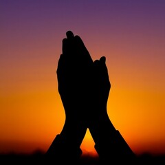 Silhouette of praying hands at sunset with concept of All Saints' Day  