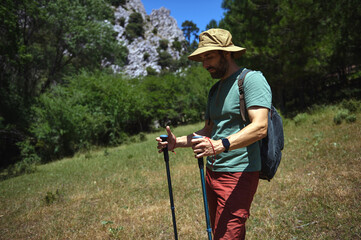 Man Hiking in Scenic Mountain Landscape Carrying Hiking Poles on a Sunny Day