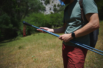 Man Holding Hiking Poles in a Sunny Forested Area on a Summer Day