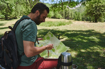 Bearded Man Exploring Nature with a Map in a Forest on a Sunny Day