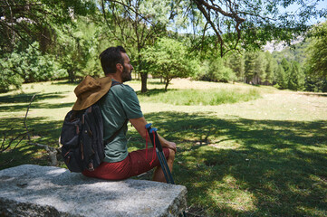 Bearded Middle Aged Man Relaxing Outdoors in a Sunny Forested Area During a Hiking Adventure