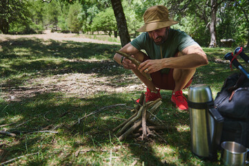 Man Preparing Campfire in Forest While Camping on a Sunny Day