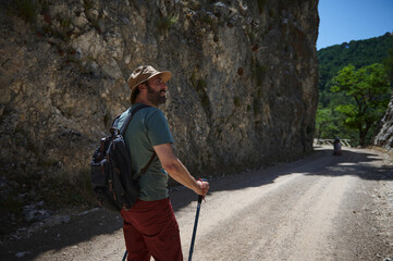 Bearded Man Hiking Through Rocky Mountain Pathway on a Sunny Day