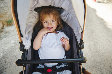 Young Child Smiling in a Stroller During an Outdoor Stroll on a Sunny Day