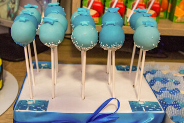 Sweet treats in the form of donuts, popsicles and popsicles are decorated with blue and white fondant with various motifs for a birthday party