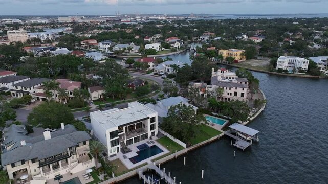 Luxury american villas with swimming pool and private river access at bayshore of Tampa, Florida. Aerial top down flyover. Noble and expensive district of american town at dusk. Mansion along shore.